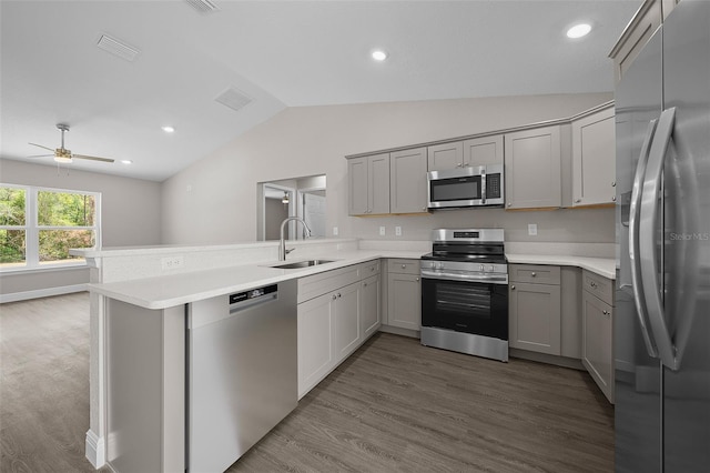 10435 SE 125th Ln, Belleview, FL 34420 - kitchen with gray cabinetry, a sink, a peninsula, vaulted ceiling, and appliances with stainless steel finishes
