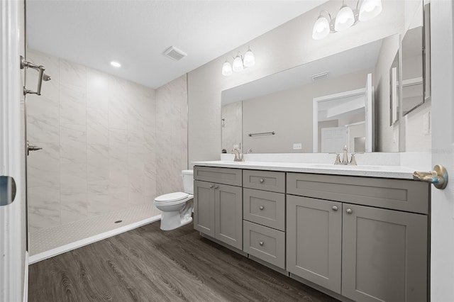 10435 SE 125th Ln, Belleview, FL 34420 - bathroom with a sink, wood finished floors, visible vents, double vanity, and tiled shower