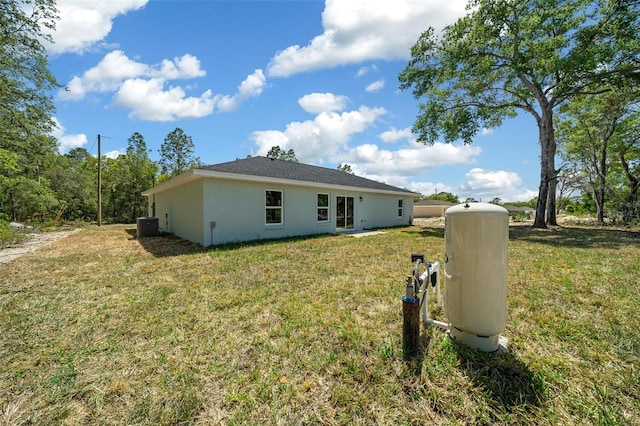 10435 SE 125th Ln, Belleview, FL 34420 - back of house with central air condition unit, a yard, and stucco siding