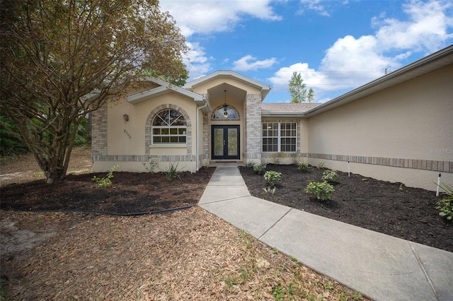 doorway to property with french doors, stone siding, and stucco siding