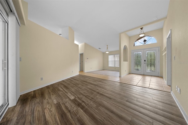 foyer entrance with a wealth of natural light, french doors, an inviting chandelier, and wood finished floors