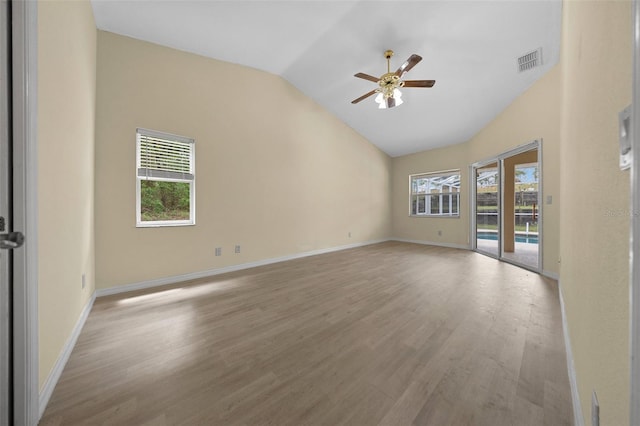 empty room featuring a ceiling fan, wood finished floors, lofted ceiling, and visible vents