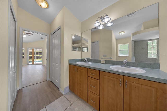 bathroom with wood finished floors, double vanity, a sink, and a healthy amount of sunlight