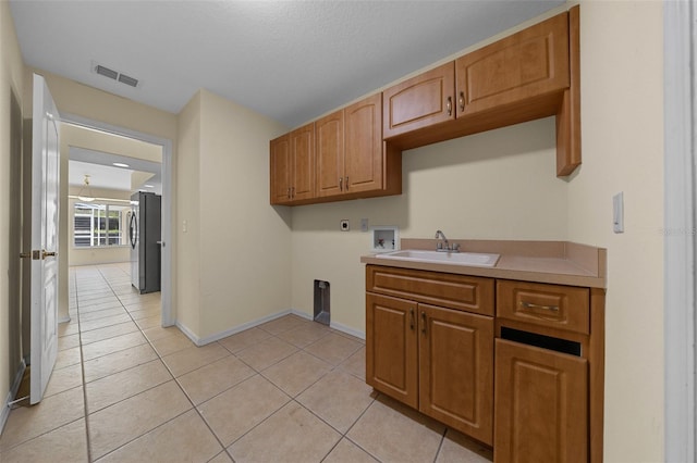 laundry area featuring electric dryer hookup, light tile patterned floors, washer hookup, visible vents, and a sink
