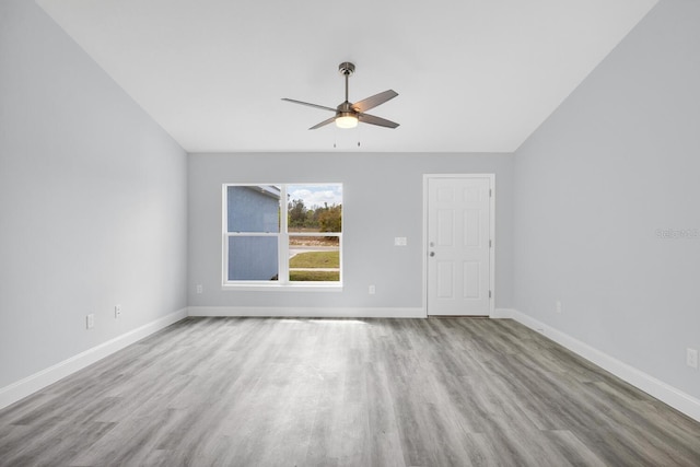 spare room with vaulted ceiling, baseboards, wood finished floors, and a ceiling fan