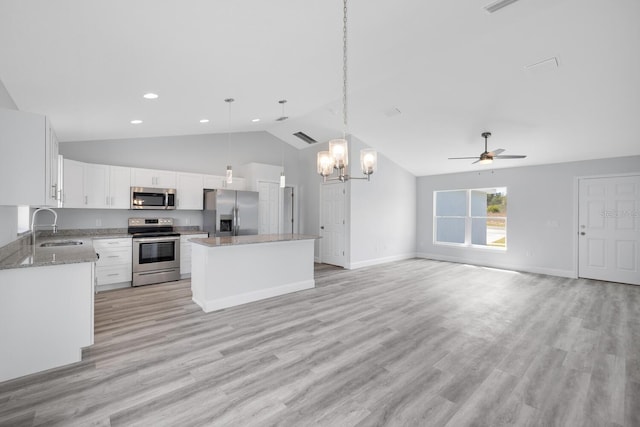 kitchen featuring a center island, a sink, ceiling fan with notable chandelier, vaulted ceiling, and appliances with stainless steel finishes