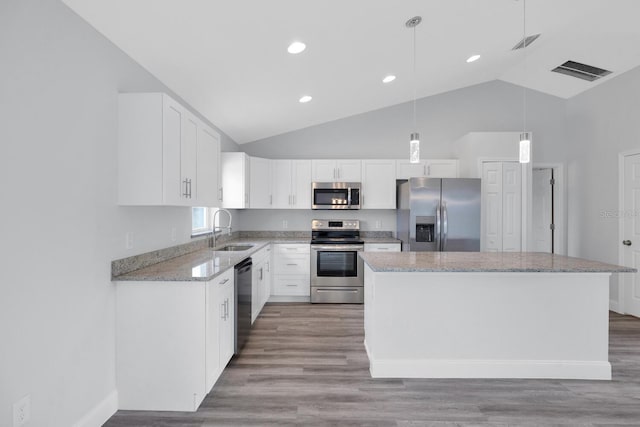 kitchen featuring light stone countertops, visible vents, a sink, a kitchen island, and appliances with stainless steel finishes