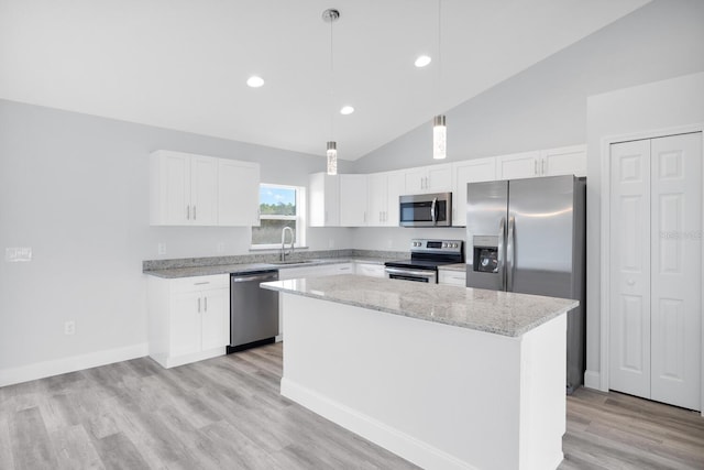 kitchen with a sink, white cabinetry, appliances with stainless steel finishes, a kitchen island, and light stone counters