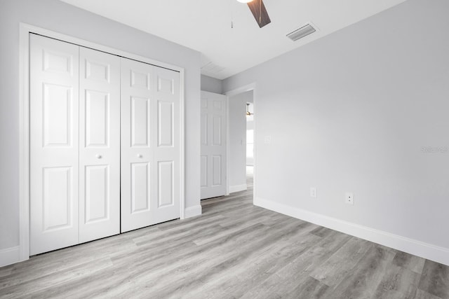 unfurnished bedroom with a closet, visible vents, wood finished floors, and baseboards