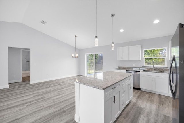 kitchen featuring a sink, lofted ceiling, light wood-type flooring, light stone countertops, and appliances with stainless steel finishes