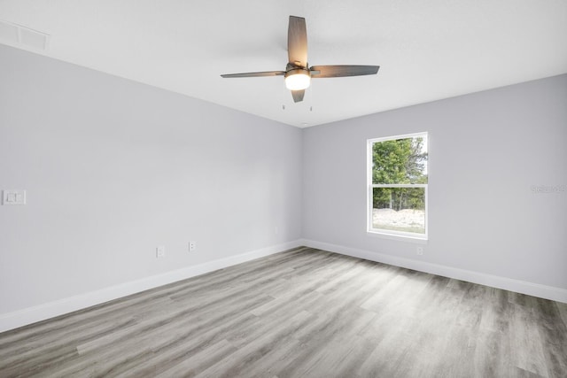 empty room with baseboards, ceiling fan, and wood finished floors