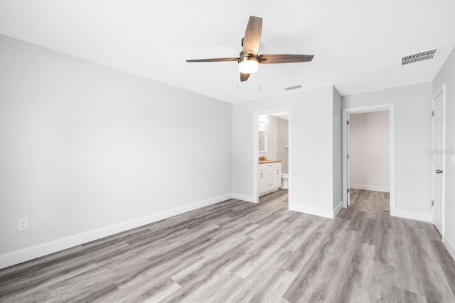 unfurnished bedroom with ensuite bathroom, visible vents, baseboards, ceiling fan, and light wood-style floors