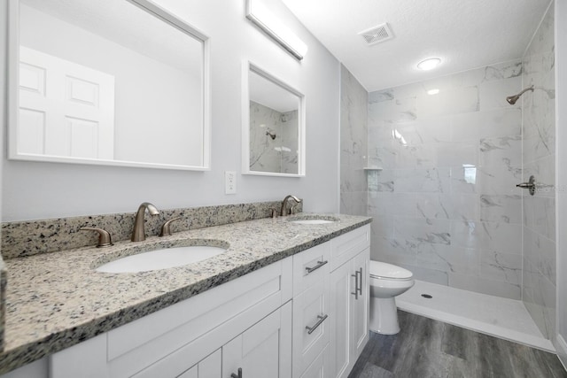 full bathroom with toilet, visible vents, wood finished floors, and a sink