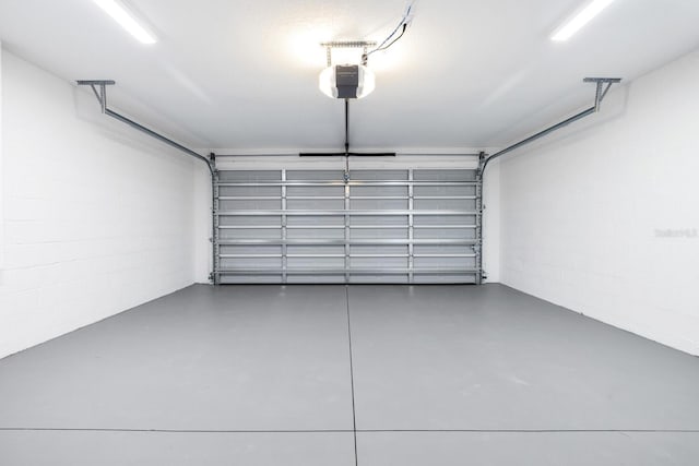 garage featuring concrete block wall and a garage door opener