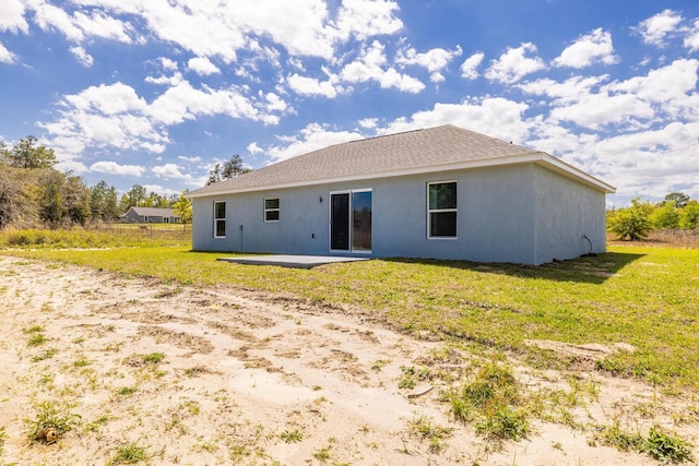 back of property with a yard, stucco siding, and a patio area