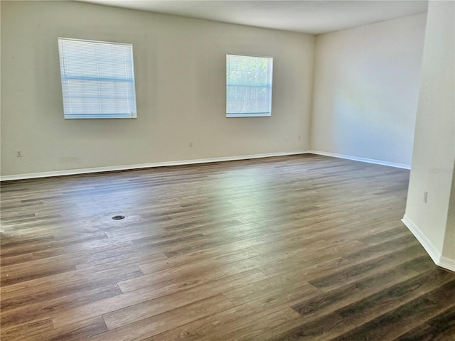 unfurnished room with baseboards and dark wood-style floors