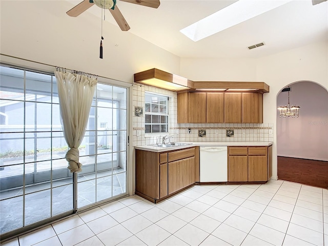 kitchen featuring light countertops, brown cabinetry, decorative backsplash, dishwasher, and a sink