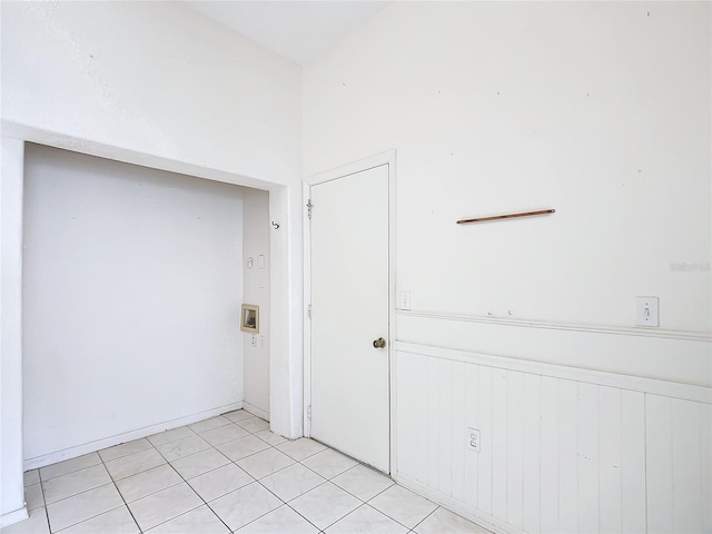 unfurnished room with light tile patterned floors and wainscoting