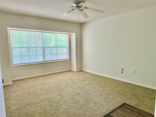 carpeted spare room with a textured ceiling, baseboards, and ceiling fan