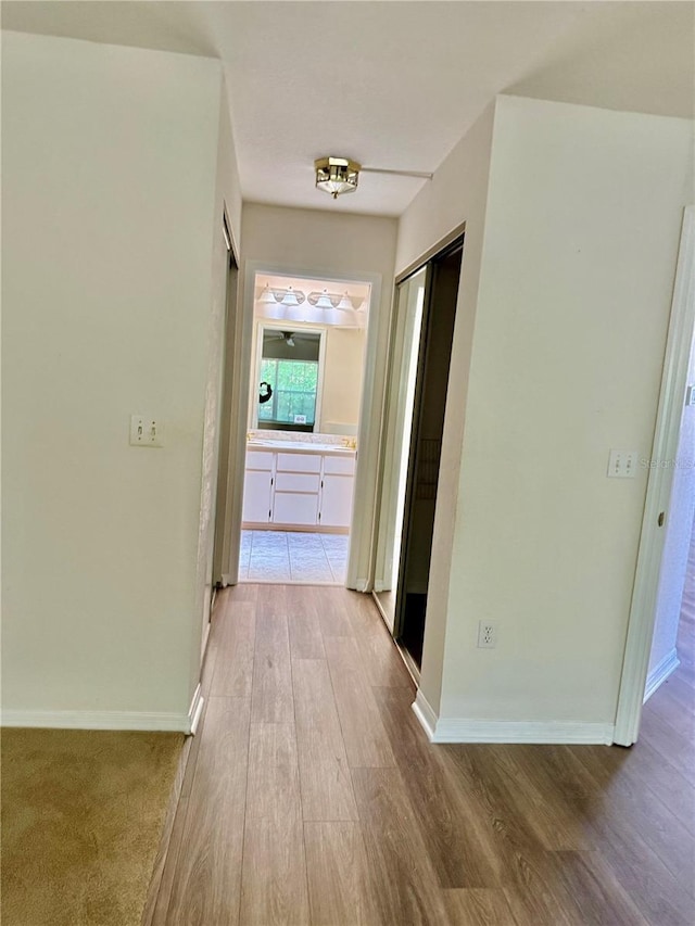 hall featuring light wood-type flooring and baseboards