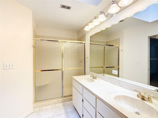 bathroom featuring a shower stall, tile patterned floors, a sink, and visible vents