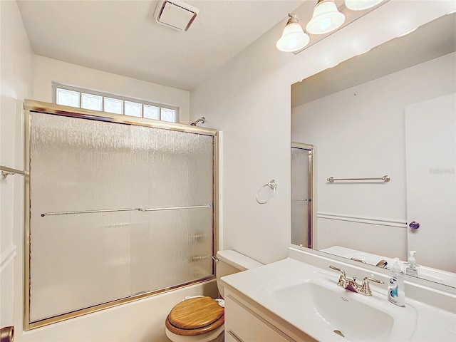 bathroom with toilet, enclosed tub / shower combo, vanity, and visible vents