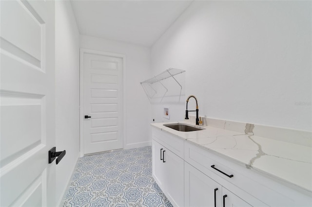 clothes washing area with washer hookup, baseboards, cabinet space, and light tile patterned floors