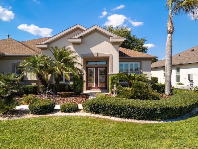 view of front of house with a front yard, stucco siding, and french doors