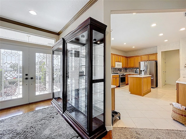 foyer entrance with ornamental molding, french doors, and recessed lighting