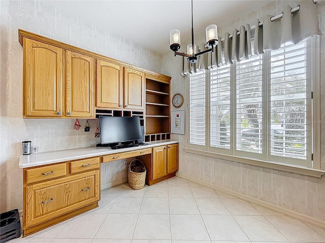 unfurnished office with built in study area, light tile patterned floors, baseboards, and an inviting chandelier