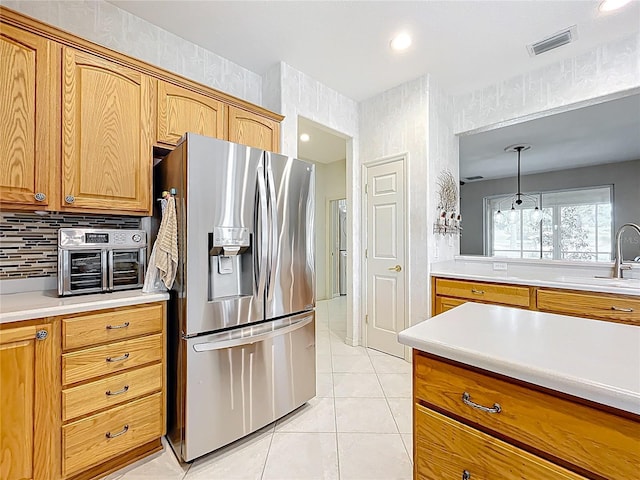 kitchen with visible vents, light tile patterned flooring, a sink, light countertops, and stainless steel fridge