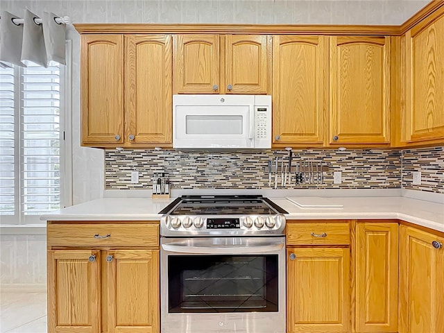 kitchen with white microwave, stainless steel electric range, decorative backsplash, and light countertops