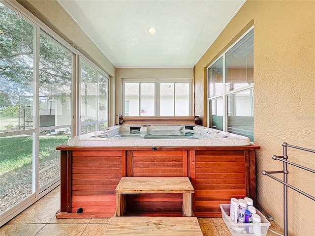 sunroom featuring tile patterned floors, a textured wall, and a hot tub