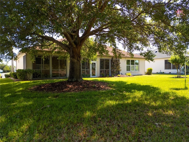 back of house with stucco siding and a lawn