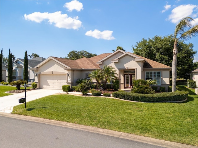view of front facade featuring a front yard, an attached garage, concrete driveway, and stucco siding