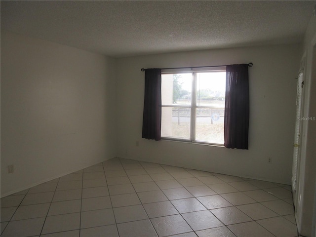 unfurnished room featuring a textured ceiling and light tile patterned floors