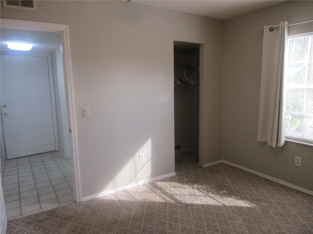 unfurnished bedroom with visible vents, carpet, a closet, and multiple windows