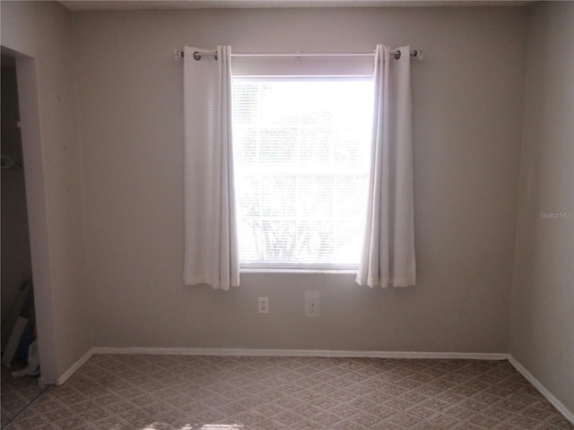 empty room featuring light carpet and baseboards