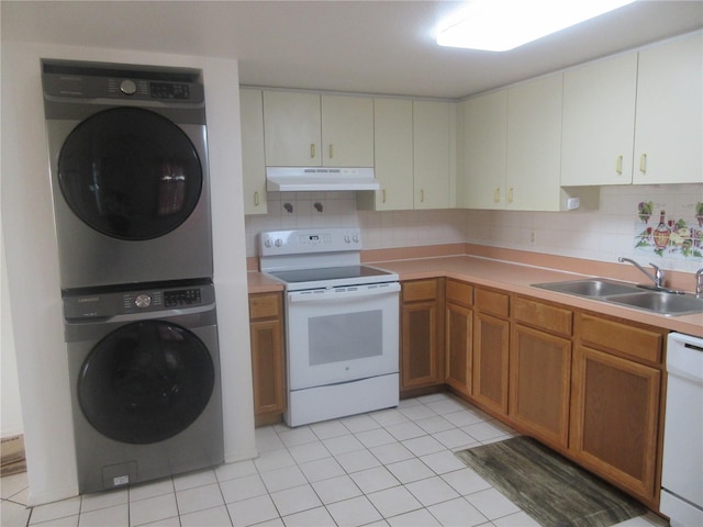 kitchen featuring under cabinet range hood, a sink, white appliances, decorative backsplash, and stacked washer and dryer