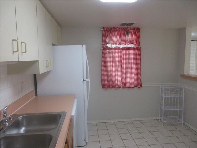 kitchen with a sink, tasteful backsplash, visible vents, white cabinetry, and light countertops
