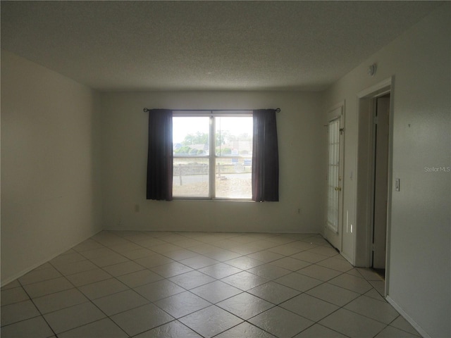 spare room featuring a textured ceiling and light tile patterned floors