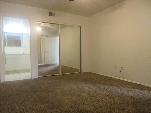 unfurnished bedroom with baseboards, visible vents, carpet, a closet, and ensuite bath