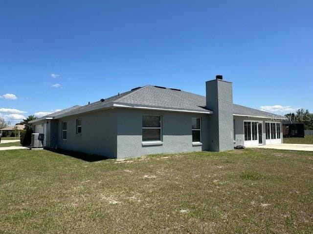 9934 SE 64th Ave, Belleview, FL 34420 - back of property with a chimney, a shingled roof, a lawn, and stucco siding