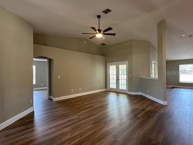 9934 SE 64th Ave, Belleview, FL 34420 - unfurnished living room featuring dark wood-style flooring, baseboards, visible vents, ceiling fan, and arched walkways