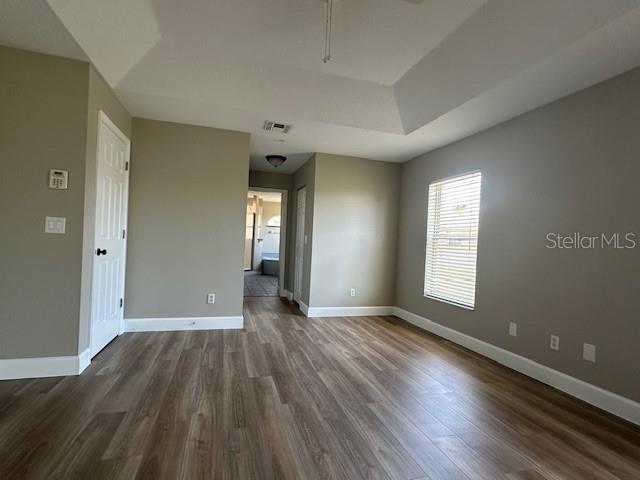 9934 SE 64th Ave, Belleview, FL 34420 - empty room with a raised ceiling, dark wood-style flooring, baseboards, and visible vents