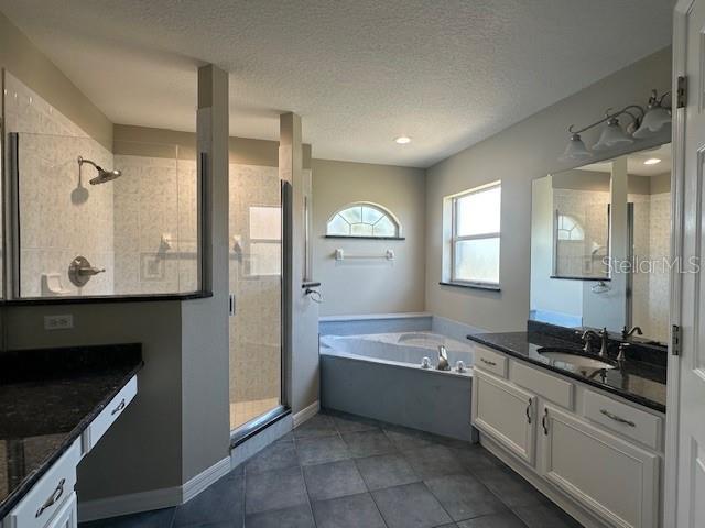 9934 SE 64th Ave, Belleview, FL 34420 - full bathroom with a textured ceiling, a shower stall, vanity, tile patterned flooring, and a garden tub