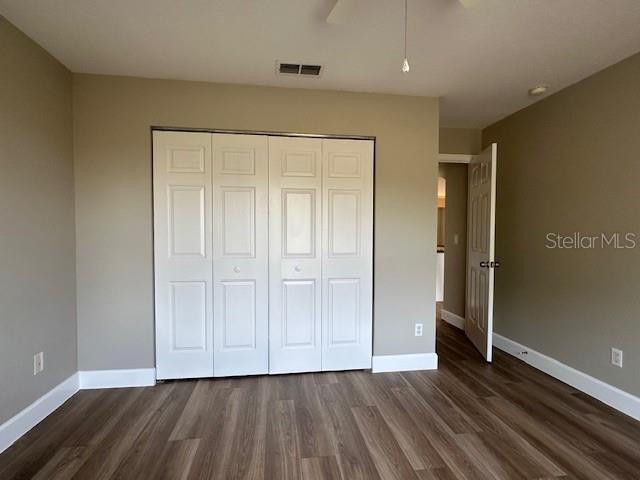 9934 SE 64th Ave, Belleview, FL 34420 - unfurnished bedroom with visible vents, baseboards, a closet, ceiling fan, and dark wood finished floors