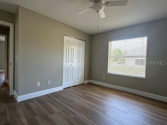 9934 SE 64th Ave, Belleview, FL 34420 - unfurnished bedroom featuring dark wood-type flooring, a closet, baseboards, and a textured ceiling