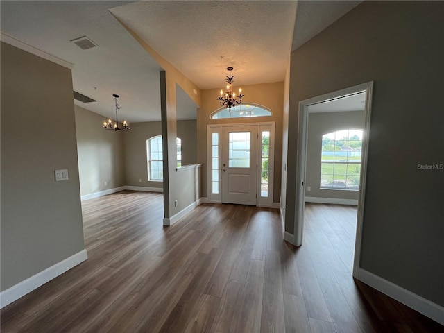 9934 SE 64th Ave, Belleview, FL 34420 - foyer entrance featuring a notable chandelier, baseboards, dark wood-style floors, a textured ceiling, and visible vents