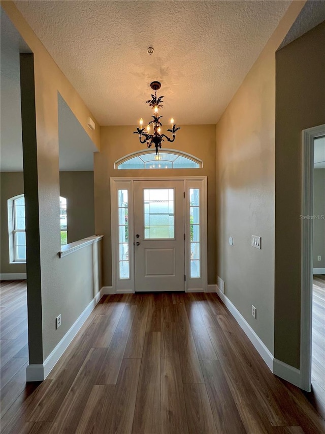 9934 SE 64th Ave, Belleview, FL 34420 - foyer entrance with a textured ceiling, an inviting chandelier, dark wood finished floors, and plenty of natural light